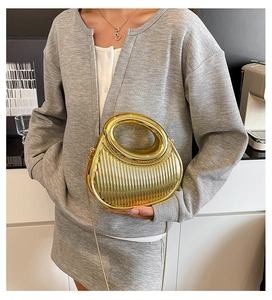 Detailed shot of gold metal evening bag with vertical stripes and round handle