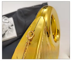 Detail of gold glossy crescent bag with polished concentric rings and chain lobster clasp