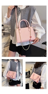 Détails d'un sac à main rose en cuir avec chaîne dorée et charms fraises rouges