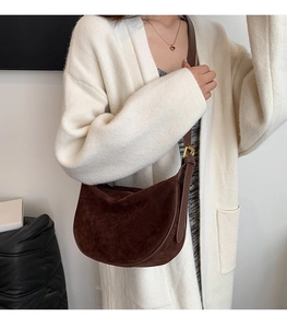 Detail of dark brown matte suede hobo bag with adjustable strap on white outfit