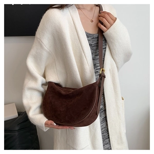 Detail of vintage brown suede shoulder bag with gold buckle on white knit sweater