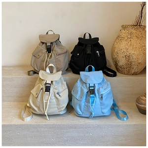 Minimalist canvas backpacks in khaki, black, and blue colors shown on stone steps