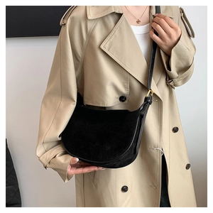 Detail of black suede hobo bag with golden hardware and adjustable leather strap