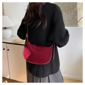 Detail of burgundy suede crescent bag showing premium matte texture and gold hardware