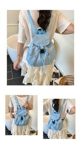 Detail view of light blue nylon backpack showing metal buckle and side pocket layout