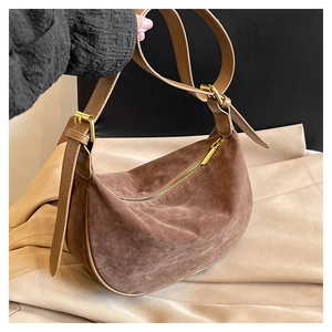 Detail of brown suede crescent bag with smooth leather strap and gold buckle