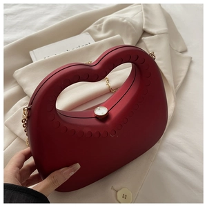 Detail van rode hartvormige acryl clutch met matte textuur en gouden ketting