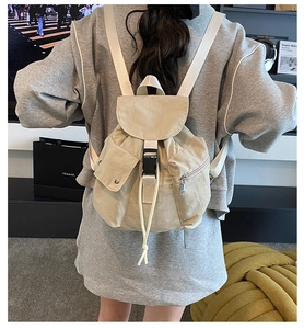 Detailed view of beige nylon drawstring backpack with buckle closure and side zipper pocket