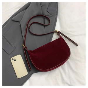 Detailed macro of the wine red suede crossbody bag placed on a grey blazer suit
