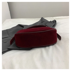 Detail of dark red velvet texture and leather piping on the retro style dumpling bag