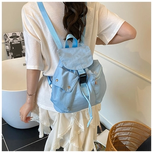 Light blue nylon backpack featuring black buckle closure and front pockets on a model