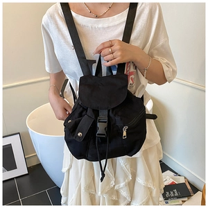 Minimalist black nylon backpack with flap closure and buckle detail shown on model