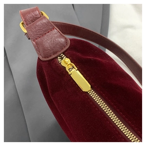 Close-up of burgundy velvet hobo bag featuring premium gold metal zipper and leather strap