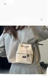 Detail of cream bucket bag with silver heart charm and elegant pearl chain strap