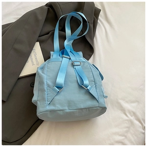 Detail of light blue nylon backpack with adjustable straps and silver metal buckles