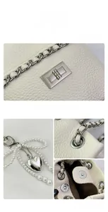 Detail of white lychee leather bucket bag with pearl chain and silver heart pendant