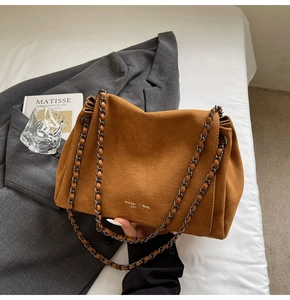 Detail of the brown suede shoulder bag featuring a chain strap and the MIRAXI logo