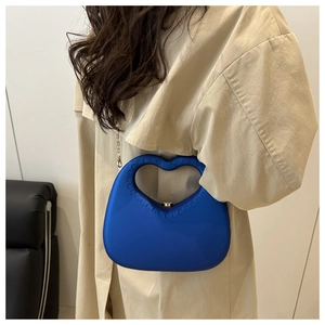 Detail van de Klein-blauwe avondtas met hartvormig handvat en een gouden ketting