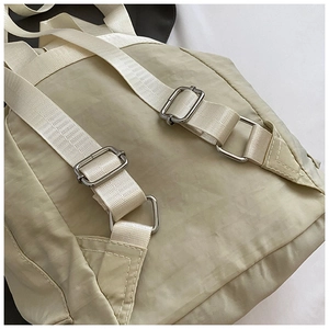 Detail of adjustable metal buckle and durable nylon strap on beige casual backpack