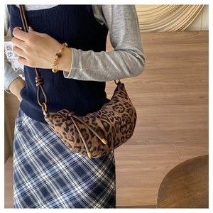 Dettaglio della borsa a mezzaluna leopardata in camoscio con tracolla in pelle e oro