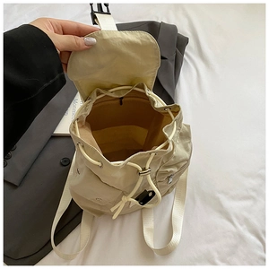 Detail view of the beige nylon backpack showing drawstring closure and inner zip pocket