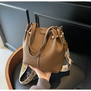 Detail of brown litchi pattern leather bucket bag with ethnic embroidered wide strap