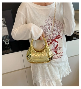 Détail du sac croissant doré à texture géométrique avec poignée anneau et chaîne