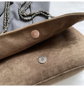 Macro shot of brown suede texture with metallic magnetic buckle and chain strap detail