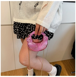 Nahaufnahme der metallisch rosa Mini-Abendtasche mit Spiralstruktur und Goldkette