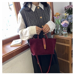 Detail of burgundy frosted leather tote with gold metal buckle and adjustable strap