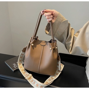 Detail of brown litchi pattern bucket bag with bohemian geometric jacquard wide strap