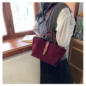 Detail of vintage burgundy frosted suede tote bag with elegant gold metal buckle clasp