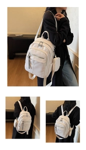 Close-up of white pebble leather backpack featuring silver zippers and a mini matching pouch