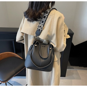 Detailed side view of a black pebble leather bucket bag with a geometric woven strap