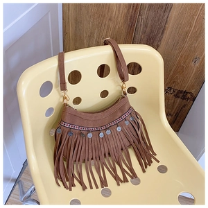 Détail du sac à bandoulière en daim marron avec franges et pendentifs argentés