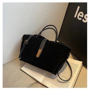 Detail of black suede tote bag featuring gold metal hardware and leather top handles