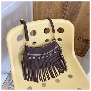 Détail du sac à bandoulière marron à franges avec ruban géométrique et pièces argentées