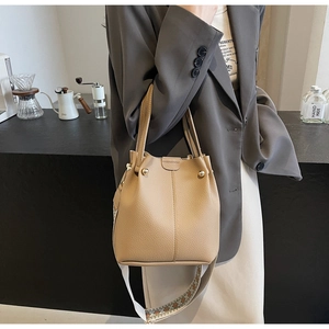 Detail view of apricot leather bucket bag with geometric embroidered wide shoulder strap