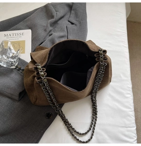 Detailed macro view of the brown suede shoulder bag with retro metal chain and interior lining