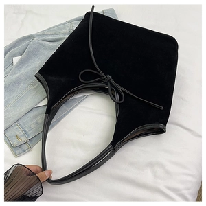Detail of black suede hobo bag with bow tie decoration on denim and white sheet