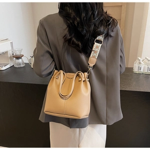 Detail of khaki bucket bag featuring textured leather and retro geometric wide strap