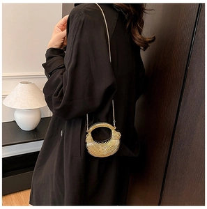 Close-up of a gold metallic crescent handbag with textured stripes and a metal chain strap
