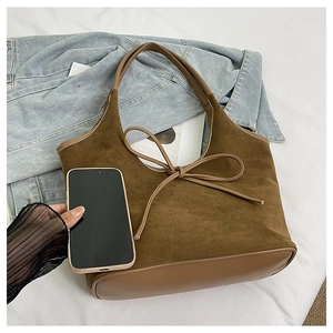 Top view of a brown suede tote bag with a bow knot, showing large capacity next to a phone
