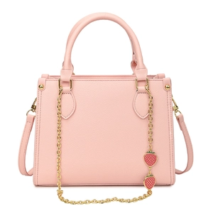 Sac à main rose texturé litchi avec chaîne dorée et breloques fraises sur fond blanc
