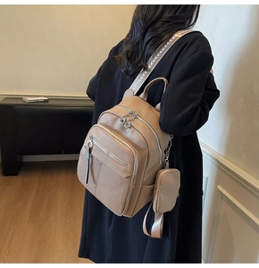 Detailed shot of khaki leather backpack with arrow patterned strap and small coin purse