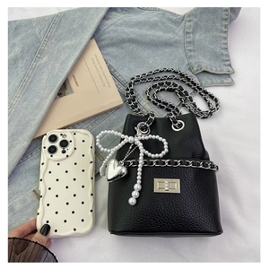 Close-up of black litchi leather bucket bag with silver chain and pearl bow charm