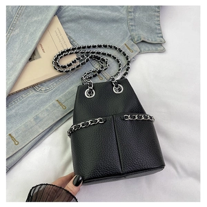 Detail of black pebbled leather bucket bag with silver metal chain and vertical stitching