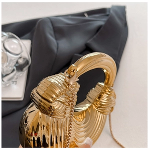 Detailed view of golden metal wave texture evening bag with circular handle and chain