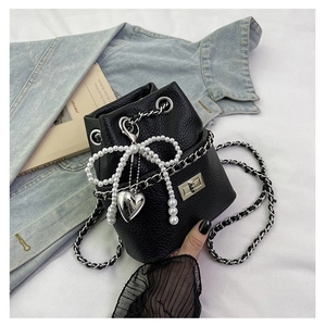 Close-up of black litchi leather bucket bag with silver chain and pearl bow charm