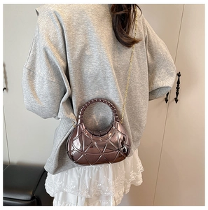 Détail d'un sac bandoulière violet métallisé avec texture géométrique et chaîne dorée